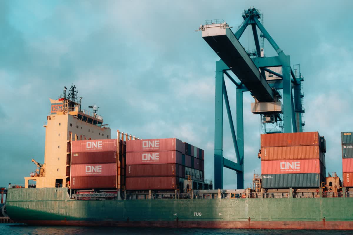 Large cargo ship loaded with colorful containers at a busy shipping port